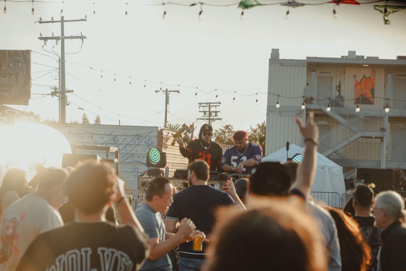 Crowd in front of the outdoor stage at golden hour, hands up