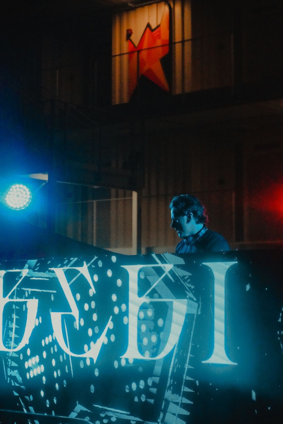 DJ behind a bright LED wall at night