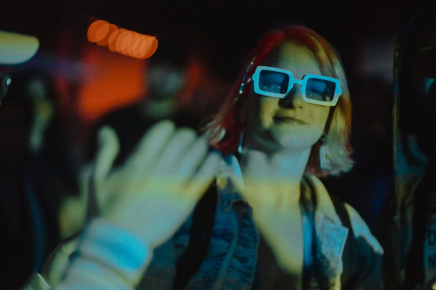 Person in white sunglasses at night under blue stage light