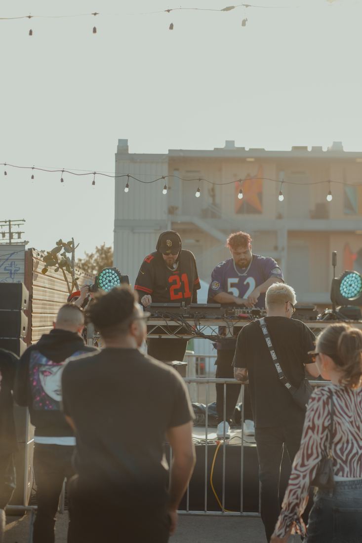 DJ at the decks on the outdoor stage with the crowd in front