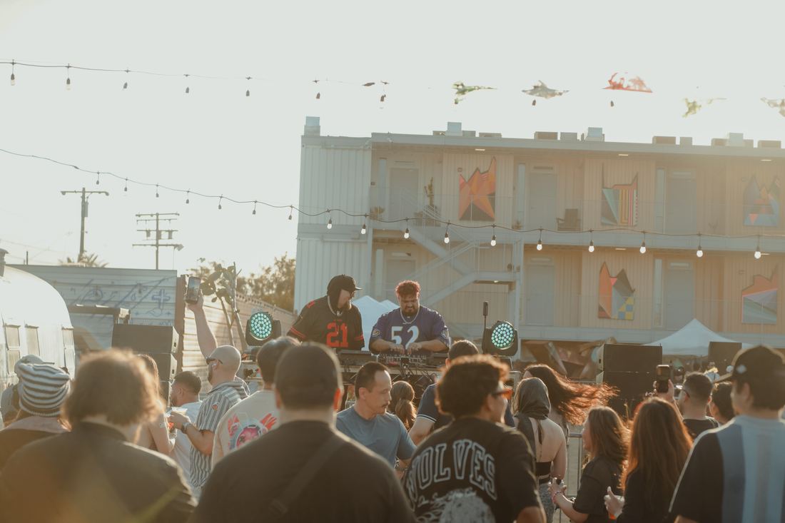 Crowd in front of the stage under string lights at the warehouse wall
