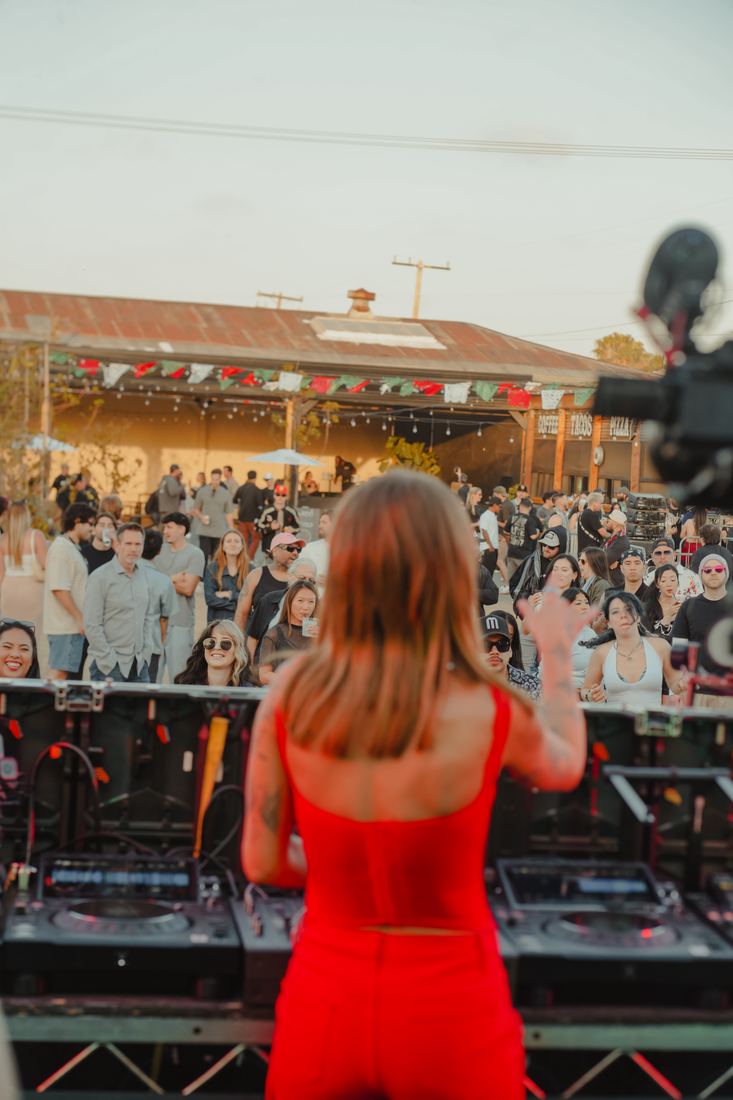 Woman in red watching the stage from the back of the crowd