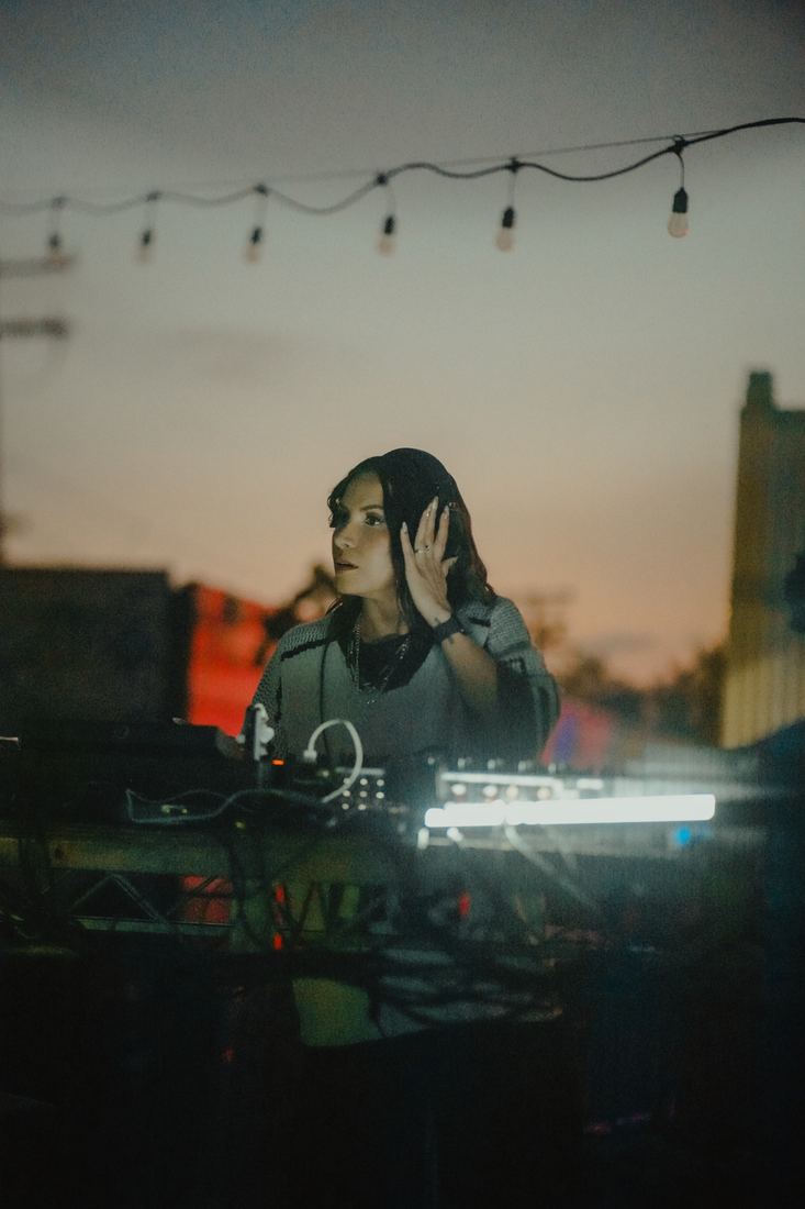 DJ at the decks at dusk under the string lights