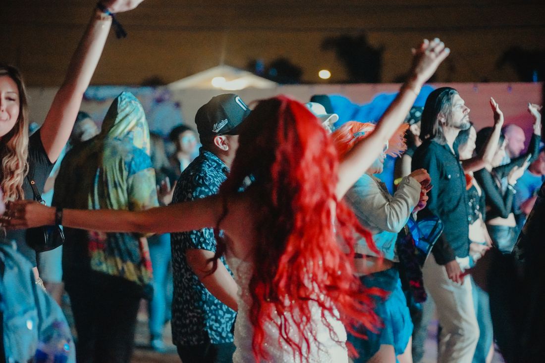 Crowd dancing with their arms up under blue light
