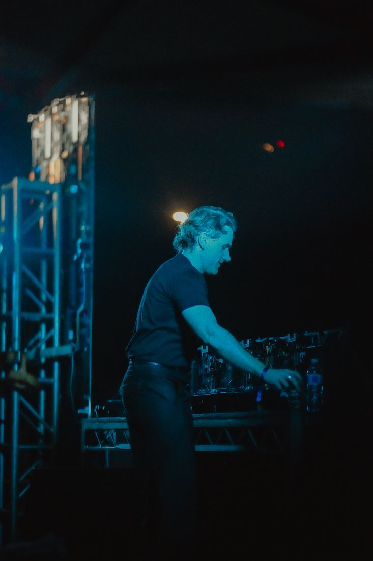 DJ alone at the decks under a cold blue wash