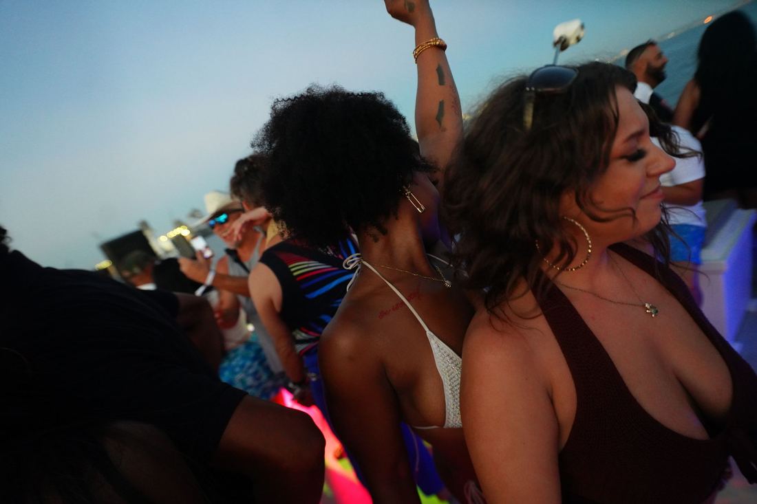 Two women dancing at dusk with their arms up