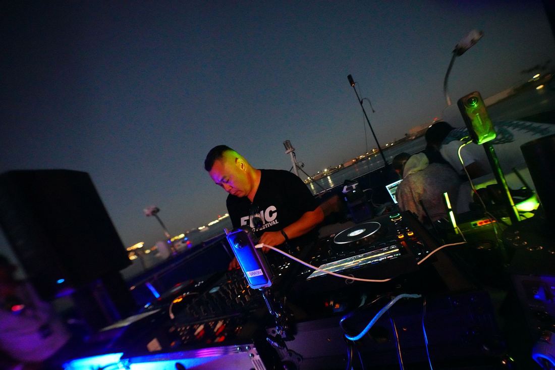 DJ at the booth at nightfall under blue and green light
