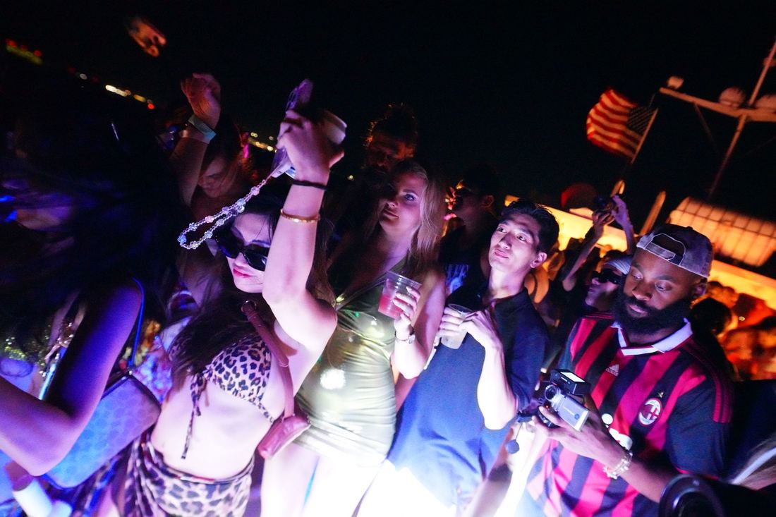 Night crowd dancing on the boat deck under pink and purple light